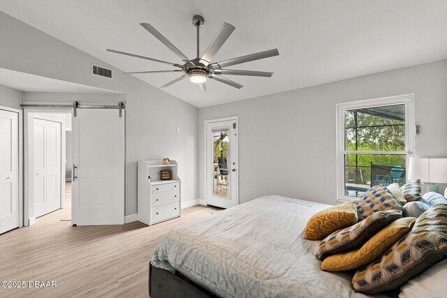 bedroom featuring vaulted ceiling, light hardwood / wood-style flooring, ceiling fan, a barn door, and access to exterior