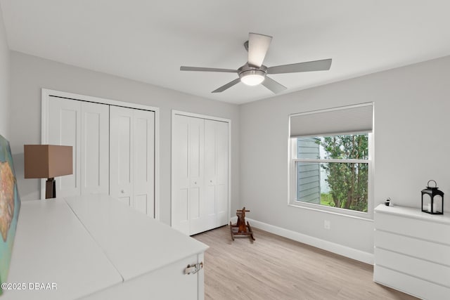 bedroom featuring ceiling fan, two closets, and light wood-type flooring