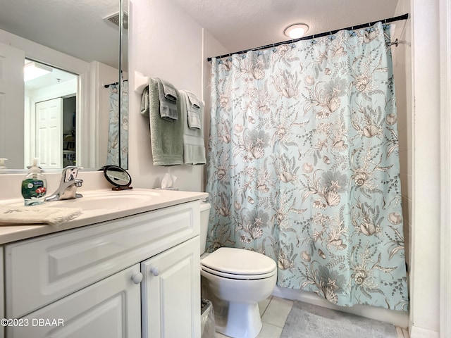 bathroom with toilet, vanity, a textured ceiling, and tile patterned floors