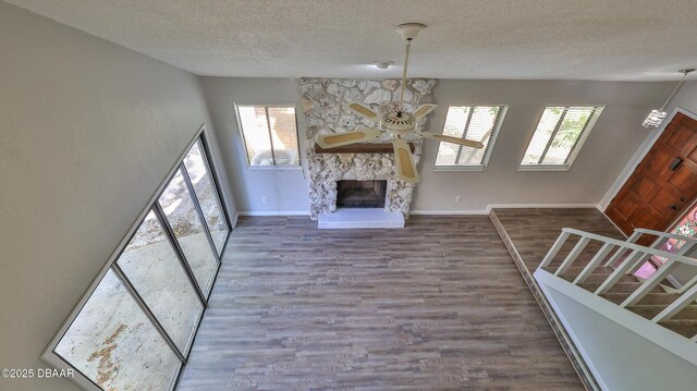 201 Pine Cone Trl, Ormond Beach, FL 32174 - unfurnished living room featuring a ceiling fan, a stone fireplace, a textured ceiling, and wood finished floors