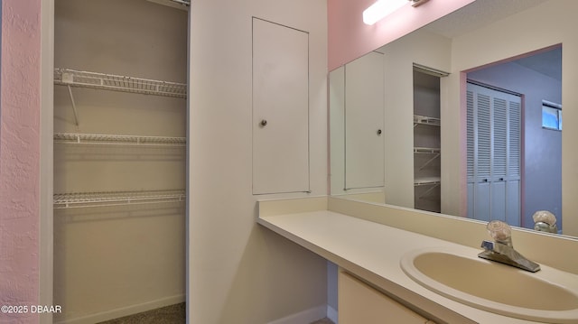 201 Pine Cone Trl, Ormond Beach, FL 32174 - bathroom featuring baseboards, vanity, and a walk in closet