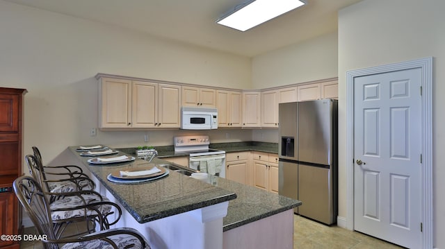 4269 Mayfair Ln, Port Orange, FL 32129 - kitchen with white appliances, a peninsula, a breakfast bar area, light tile patterned floors, and dark stone counters