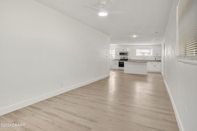 unfurnished living room with ceiling fan and light wood-type flooring