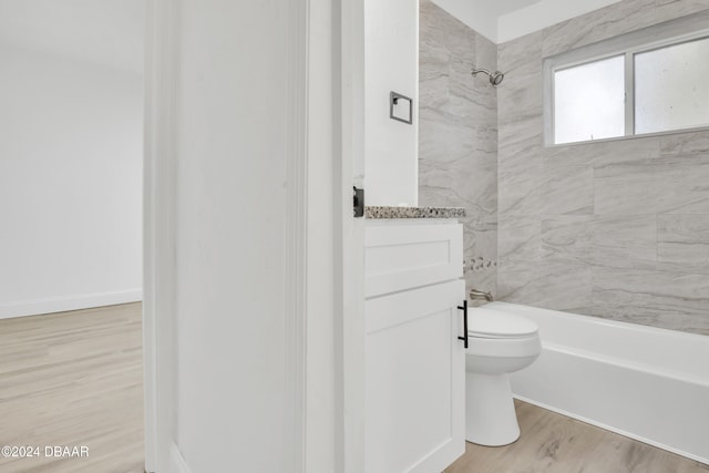 full bathroom featuring wood-type flooring, tiled shower / bath combo, toilet, and vanity