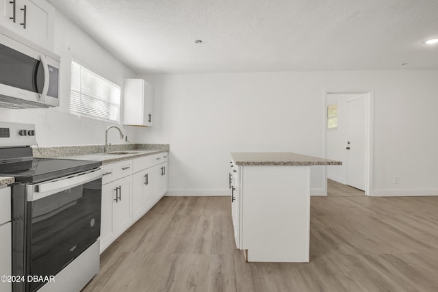 kitchen featuring white cabinetry, stainless steel appliances, a healthy amount of sunlight, and a kitchen island