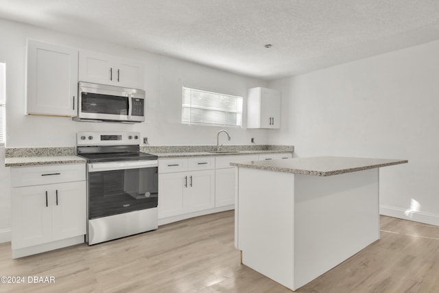 kitchen featuring white cabinetry, light wood-type flooring, stainless steel appliances, and a kitchen island