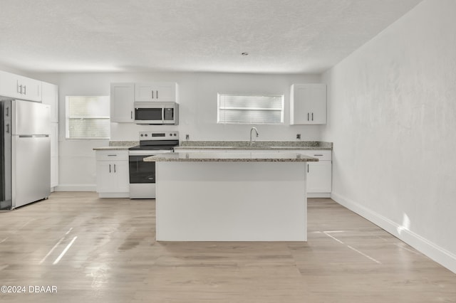 kitchen featuring a kitchen island, white cabinets, and stainless steel appliances