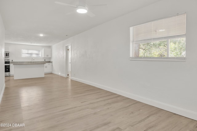 unfurnished living room with light wood-type flooring, ceiling fan, and sink