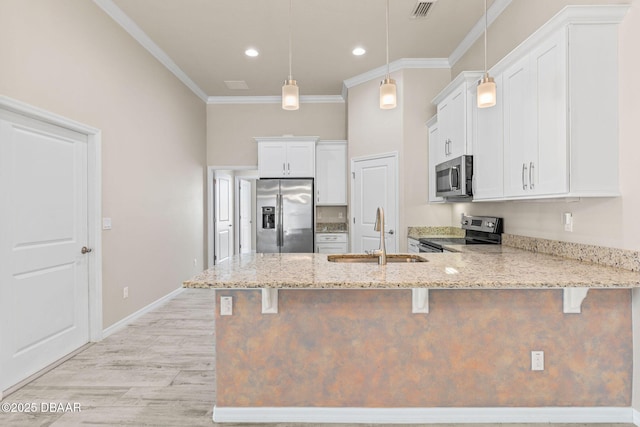 3402 Torre Blvd, New Smyrna Beach, FL 32168 - kitchen featuring stainless steel appliances, a sink, a kitchen bar, white cabinets, and a peninsula