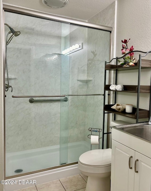 bathroom with vanity, a shower with door, tile patterned floors, toilet, and a textured ceiling