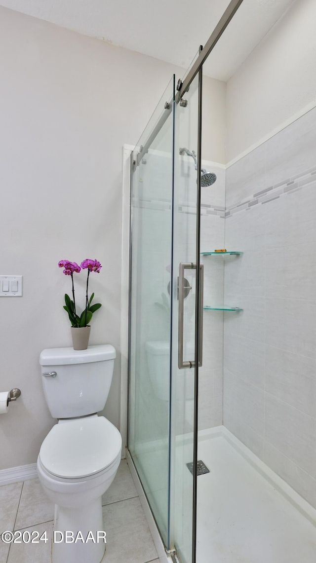 bathroom with tile patterned flooring, toilet, and a shower with door