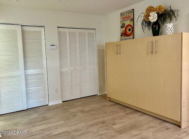 unfurnished bedroom featuring multiple closets and light hardwood / wood-style floors