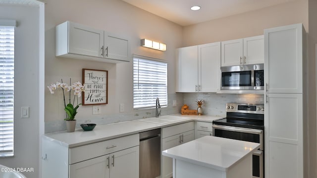 kitchen featuring white cabinets, appliances with stainless steel finishes, decorative backsplash, and sink