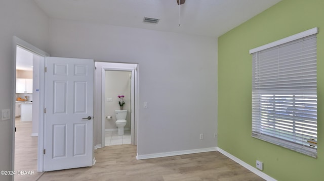 unfurnished bedroom featuring ensuite bath and light hardwood / wood-style flooring