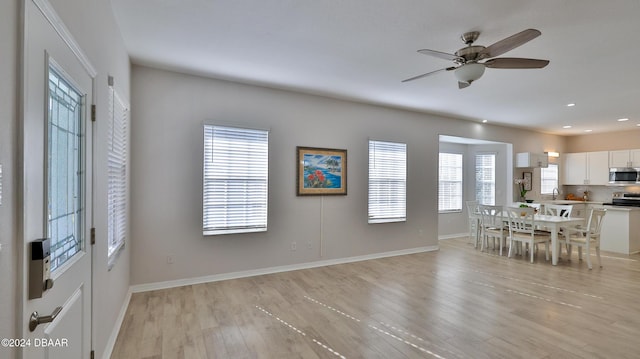 unfurnished dining area with ceiling fan, a healthy amount of sunlight, and light wood-type flooring