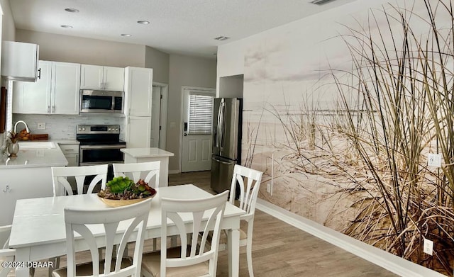 kitchen featuring a textured ceiling, stainless steel appliances, sink, white cabinets, and light hardwood / wood-style floors