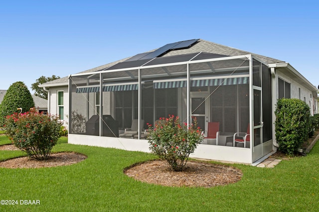 rear view of property with a lawn, a sunroom, and glass enclosure