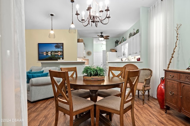 dining area with hardwood / wood-style floors and ceiling fan with notable chandelier