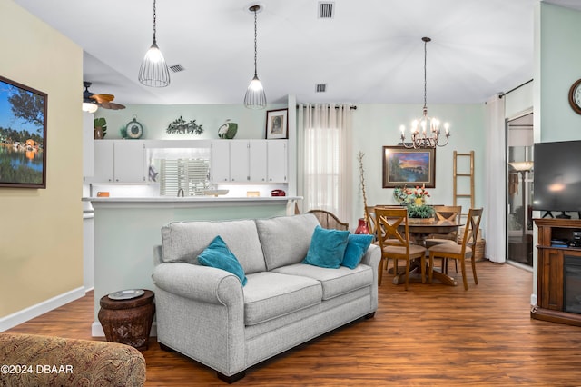 living room with ceiling fan with notable chandelier and dark hardwood / wood-style flooring