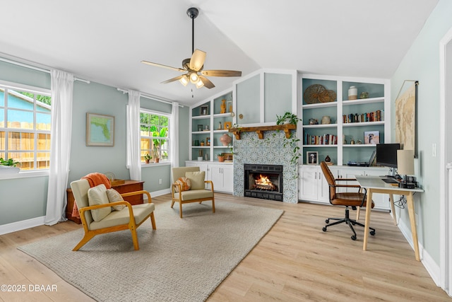 1245 Thomas Dr, Port Orange, FL 32129 - home office featuring lofted ceiling, light wood-style floors, a lit fireplace, baseboards, and a ceiling fan