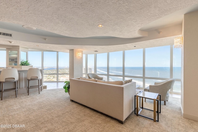 carpeted living room featuring a water view and a wall of windows