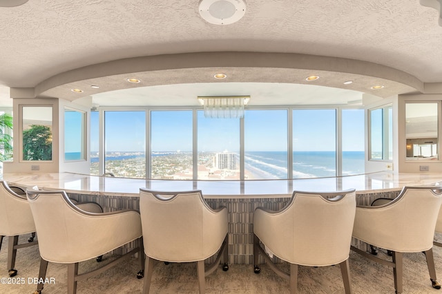 dining room with a water view, a textured ceiling, and a wealth of natural light