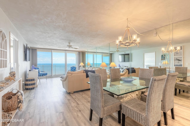 dining room with ceiling fan with notable chandelier, light hardwood / wood-style flooring, and expansive windows