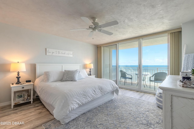 bedroom with a water view, ceiling fan, access to exterior, and hardwood / wood-style floors