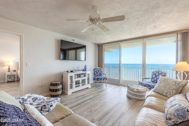 living room featuring light hardwood / wood-style flooring, expansive windows, and ceiling fan