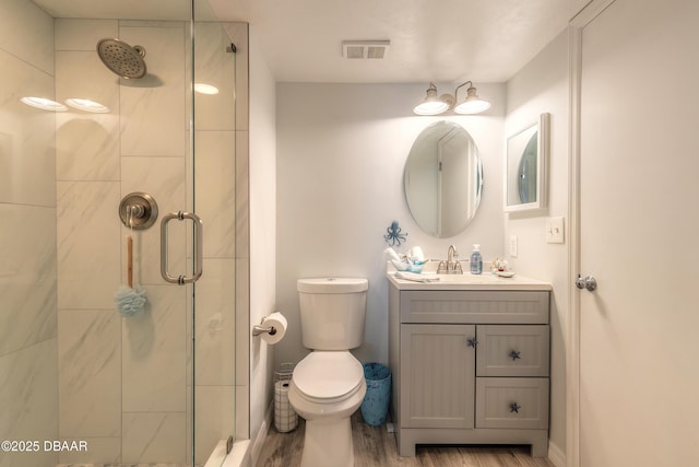 bathroom with vanity, hardwood / wood-style flooring, a shower with shower door, and toilet