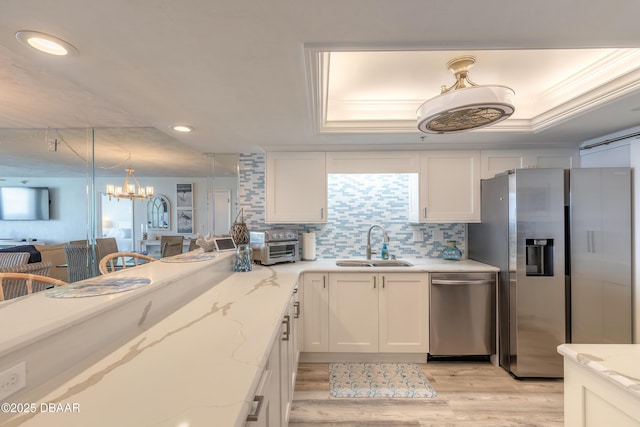 kitchen featuring appliances with stainless steel finishes, decorative light fixtures, sink, white cabinets, and light stone countertops