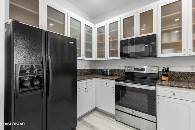 kitchen featuring black appliances, light wood-type flooring, white cabinetry, and dark stone counters