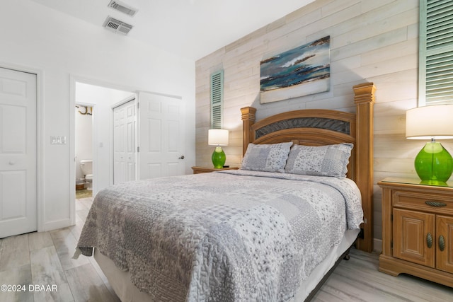 bedroom with ensuite bathroom and light hardwood / wood-style flooring