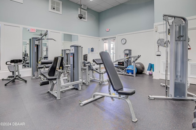 workout area featuring a paneled ceiling and a high ceiling