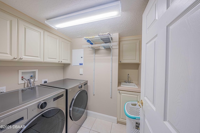 clothes washing area with a textured ceiling, cabinets, sink, independent washer and dryer, and light tile patterned floors