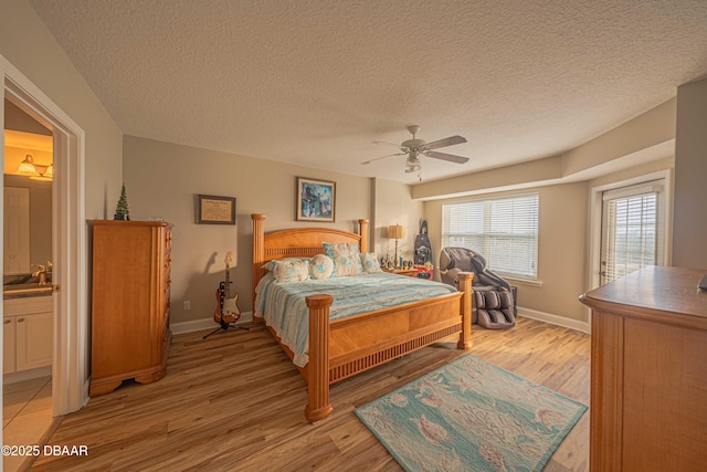 bedroom featuring ceiling fan, light hardwood / wood-style floors, a textured ceiling, and ensuite bath