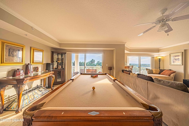 game room featuring ceiling fan, a textured ceiling, ornamental molding, and a healthy amount of sunlight