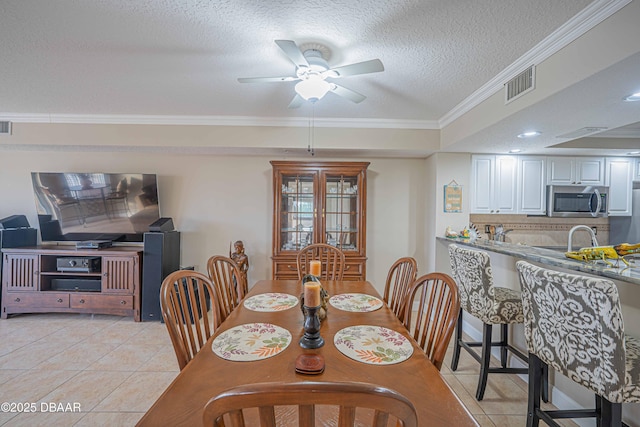 tiled dining space featuring crown molding, sink, a textured ceiling, and ceiling fan