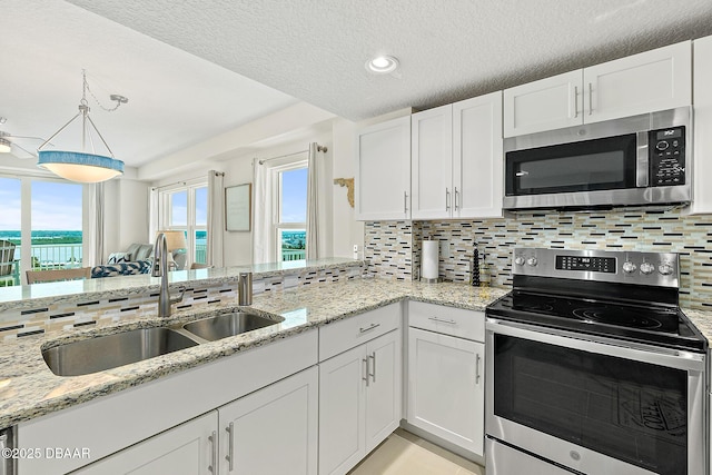3721 S Atlantic Ave Unit 801, Daytona Beach Shores, FL 32116 - kitchen featuring stainless steel appliances, white cabinetry, decorative backsplash, light stone countertops, and a textured ceiling