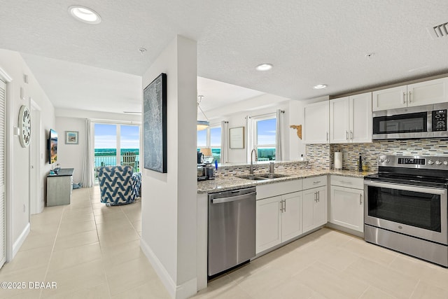 3721 S Atlantic Ave Unit 801, Daytona Beach Shores, FL 32116 - kitchen with appliances with stainless steel finishes, decorative backsplash, light stone countertops, white cabinetry, and recessed lighting