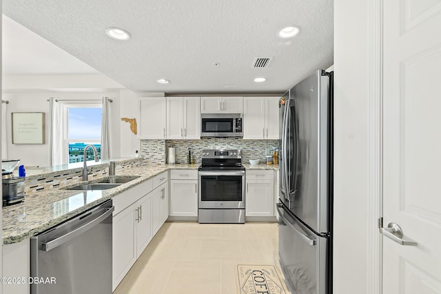 3721 S Atlantic Ave Unit 801, Daytona Beach Shores, FL 32116 - kitchen with appliances with stainless steel finishes, white cabinetry, a textured ceiling, decorative backsplash, and light stone countertops