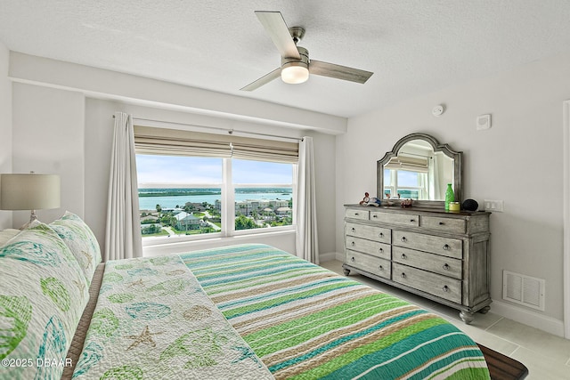 3721 S Atlantic Ave Unit 801, Daytona Beach Shores, FL 32116 - bedroom featuring a water view, a textured ceiling, a ceiling fan, and light tile patterned floors