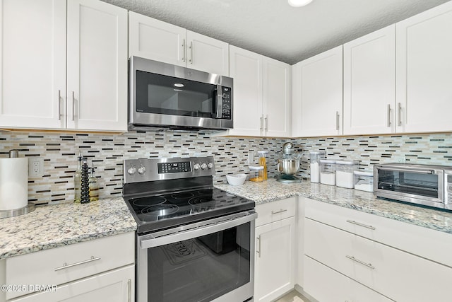3721 S Atlantic Ave Unit 801, Daytona Beach Shores, FL 32116 - kitchen with stainless steel appliances, white cabinets, backsplash, and light stone countertops