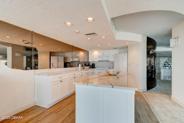 kitchen featuring white cabinetry, white appliances, a large island, and light wood-type flooring