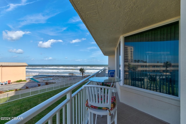 balcony featuring a view of the beach and a water view