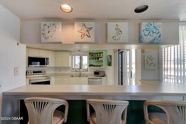 kitchen with white cabinetry, kitchen peninsula, sink, and stainless steel appliances