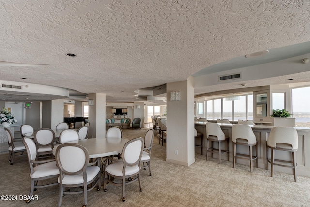 dining space with a textured ceiling and light colored carpet