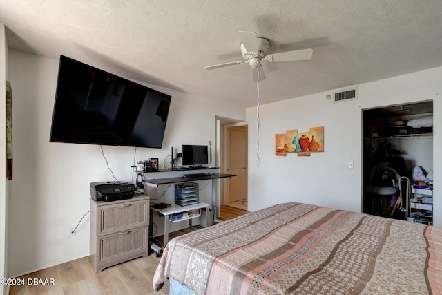 bedroom with ceiling fan, a textured ceiling, a closet, and light hardwood / wood-style flooring