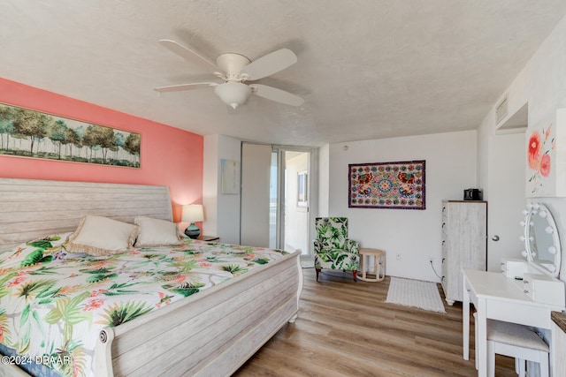 bedroom with a textured ceiling, light wood-type flooring, and ceiling fan