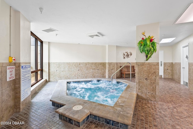 view of pool with a skylight and an indoor in ground hot tub